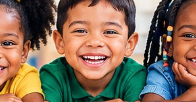 A group of smiling preschool children side by side at a classroom table