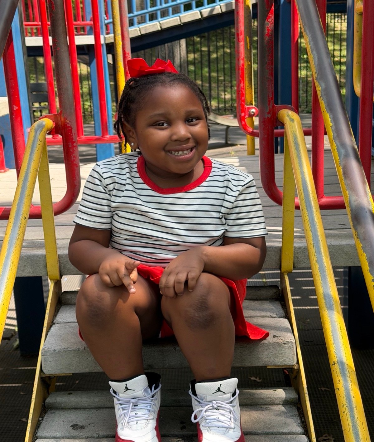 A young EVY learner smiling on the playground steps