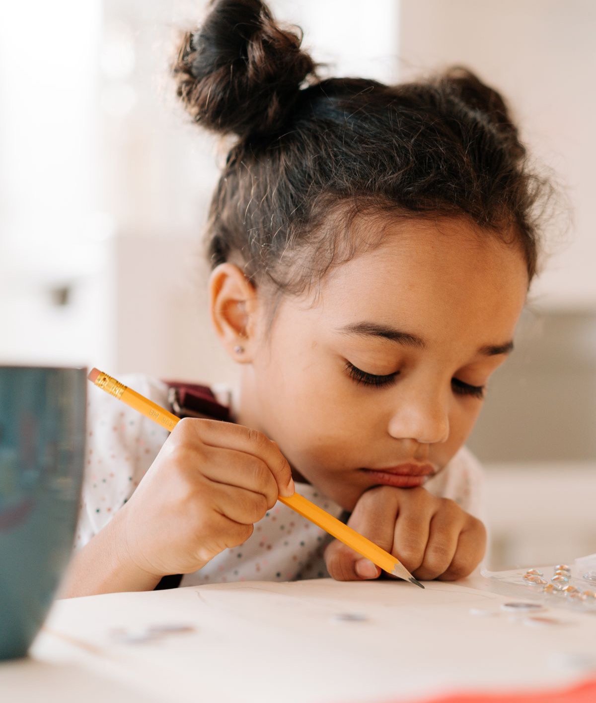 A girl concentrating as she writes with a pencil